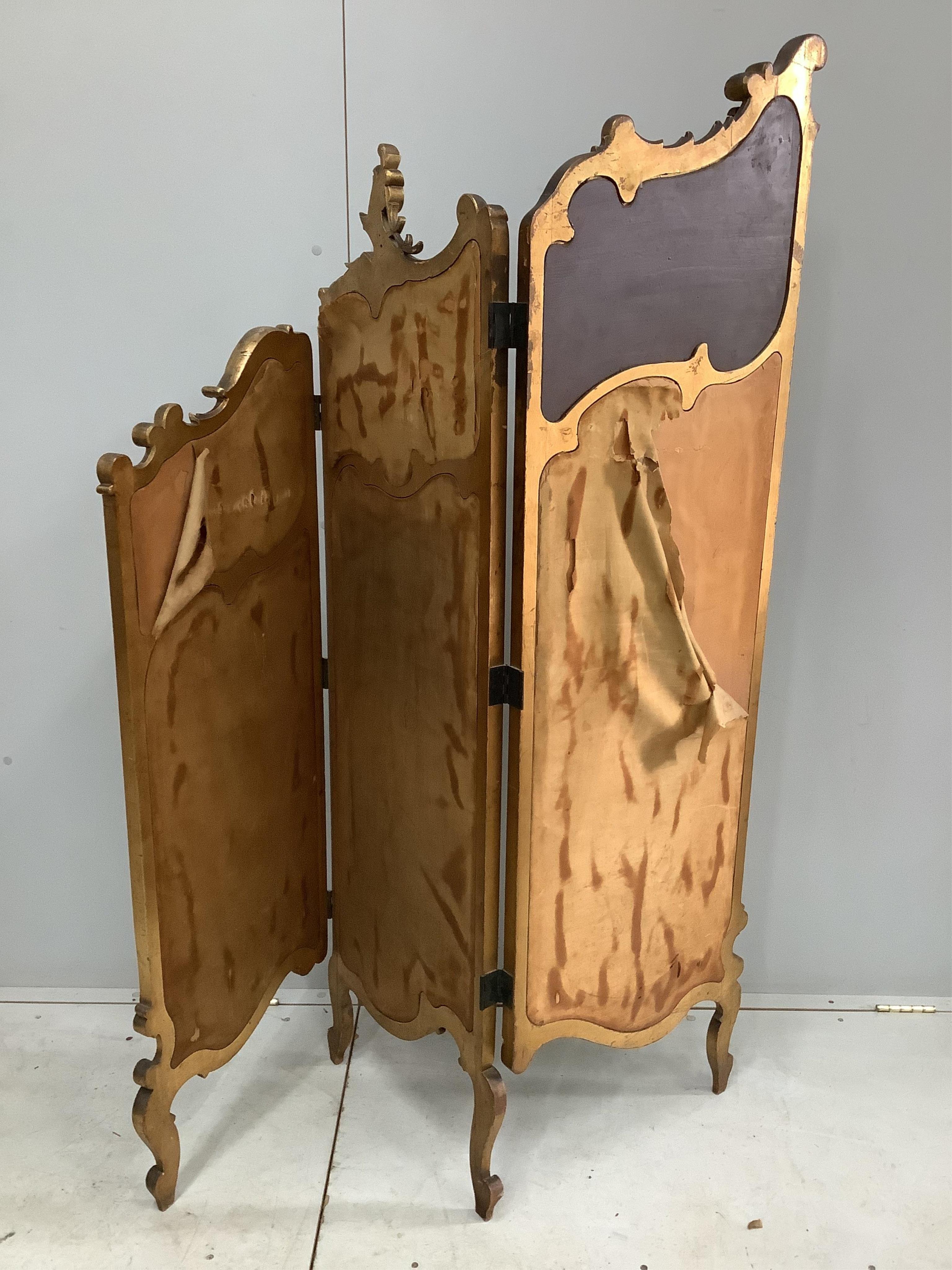 An early 20th century French carved giltwood three fold dressing screen with inset painted and printed panels, width 48cm, height 159cm. Condition - fair but some denting to the panels